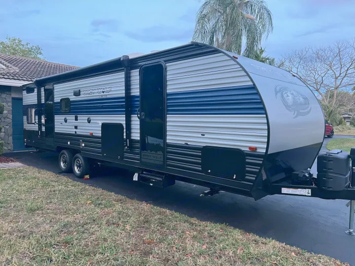 A modern Grey Wolf travel trailer, ready for RV rental, parked on a residential driveway, showcasing its sleek design.. Forest River Cherokee Grey Wolf 2022