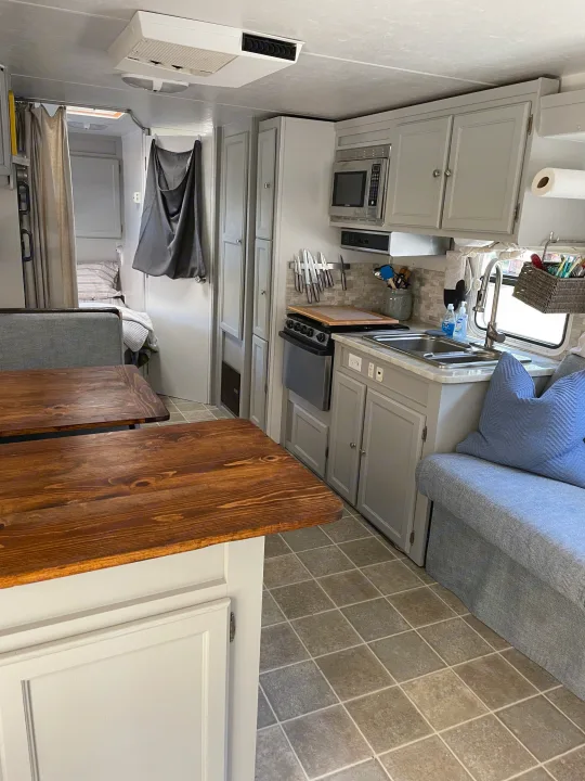 Updated rv rental interior with a bright light gray kitchen, wooden dining tables, and comfortable bench seating.. R-Vision Trail-Lite Trail-Cruiser 2004