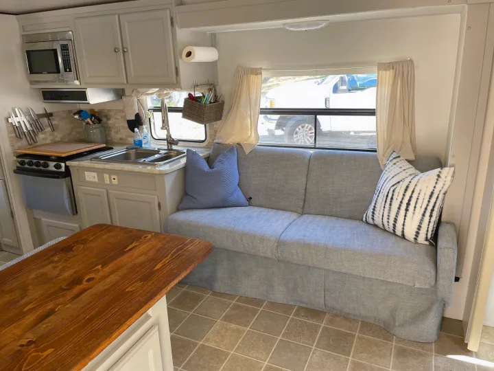 Modern RV rental interior with gray kitchen, cozy patterned sofa, wood table, and window view. Ready for your adventure!. R-Vision Trail-Lite Trail-Cruiser 2004