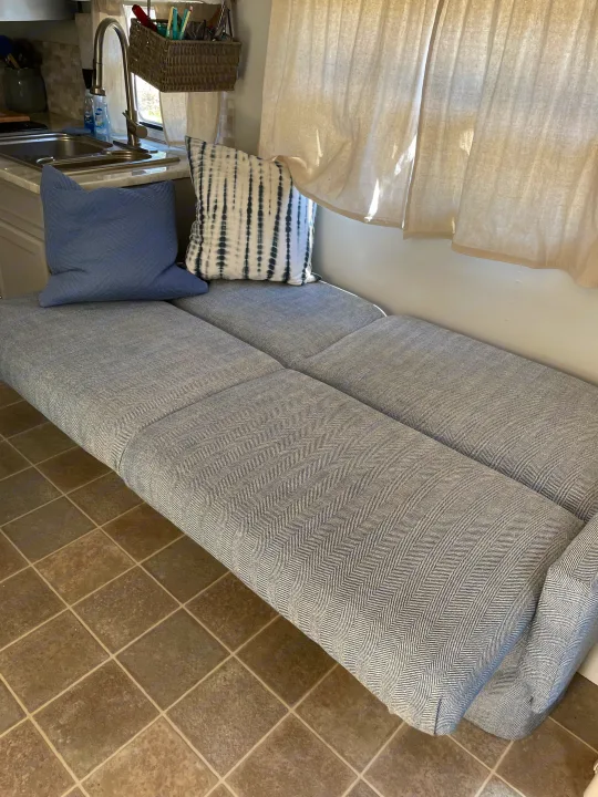 Cozy RV rental interior featuring herringbone bench seating with pillows, a compact kitchen, and neutral curtains.. R-Vision Trail-Lite Trail-Cruiser 2004