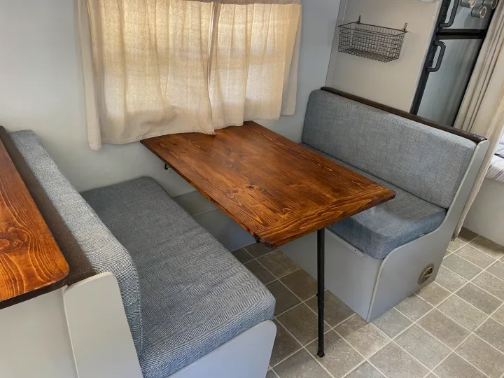 Cozy RV rental dinette featuring herringbone cushions, a wooden table, and practical wall-mounted storage for comfortable travel.. R-Vision Trail-Lite Trail-Cruiser 2004