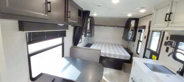 Discover the spacious interior of this RV rental, featuring a dining area, cozy bedroom with plaid bedding, and a functional kitchen.. Jayco Jay Flight 2022