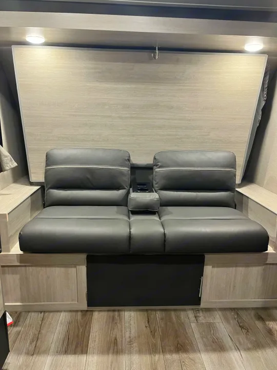 RV rental: Modern interior featuring dark grey convertible sofa with cup holders, wood panel wall, and floor storage.. Forest River Catalina Summit 184BHS 2022