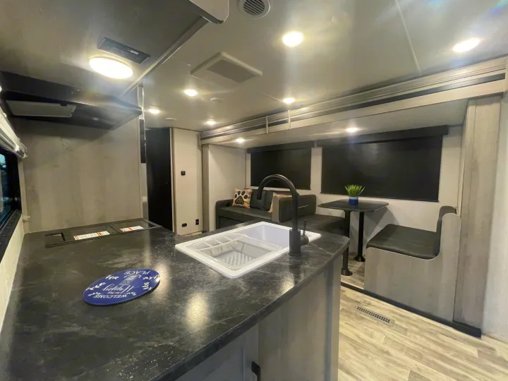 Well-lit RV rental interior featuring a modern kitchen island, cozy sofa, and compact dining area.. Dutchman Kodiak SE 2022