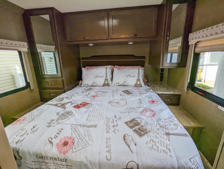 Cozy RV rental bedroom with Paris-themed bedding, compact storage, and windows.. Thor Four Winds 2020