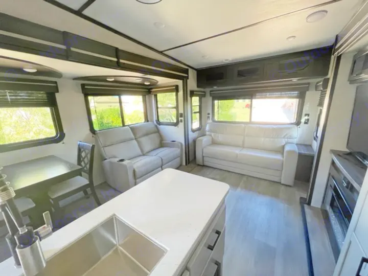 Spacious RV rental interior with modern kitchen island, dining table, and two comfy sofas in the bright living area.. Crossroads RV Cruiser Aire 2021