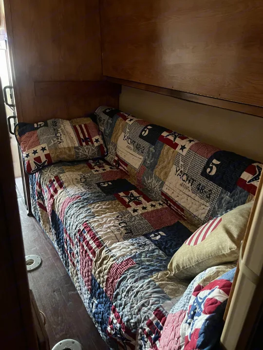Cozy RV rental interior with a patriotic quilted bench bed, wooden cabin details, and floor mounts.. Airstream Skydeck 2008