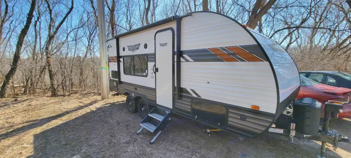 This RV rental, a Wildwood Lite travel trailer, is parked outdoors in a wooded area, ready for adventure.. Forest River Wildwood X-Lite 2020