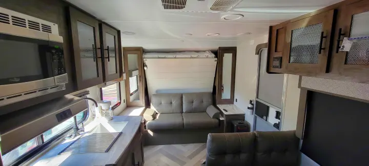 Experience comfortable RV rental living: Kitchen, sofa, and a cleverly designed fold-down bed in a bright interior.. Forest River Wildwood X-Lite 2020