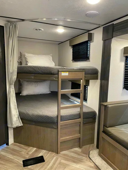 Inside this RV rental, dual bunk beds with ladder and privacy curtain offer cozy sleeping. Ideal for family trips.. Keystone RV Hideout 2021
