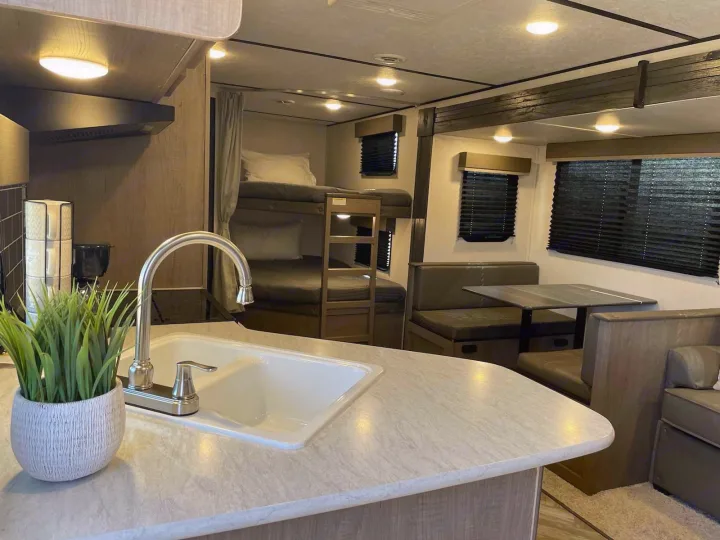RV rental interior: kitchen with sink, cozy bunk beds, and a comfortable dinette. Ready for your next adventure!. Keystone RV Hideout 2021