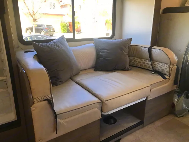 RV rental interior with comfortable dinette seating, pillows, and a bright window view, ideal for travel.. Forest River Coachmen Freelander 2019