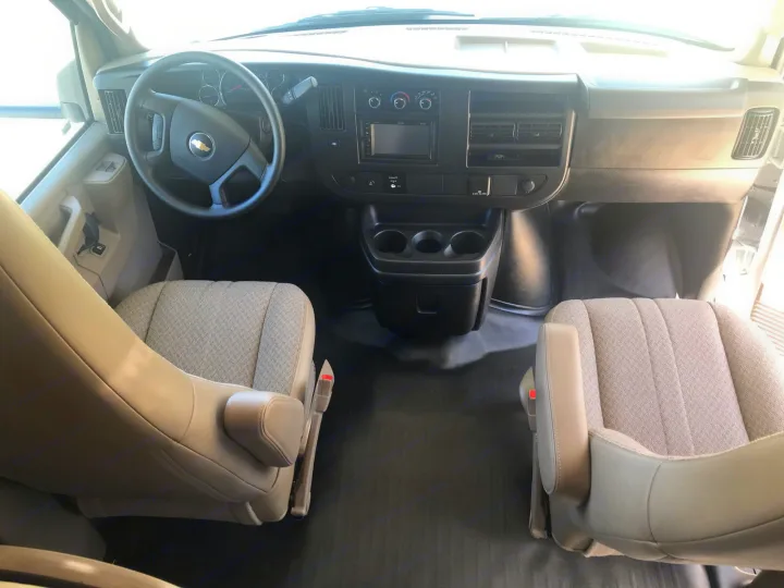 Spacious front interior of an RV rental: dashboard, steering wheel, captain's chairs, and center console for comfortable travel.. Forest River Coachmen Freelander 2019