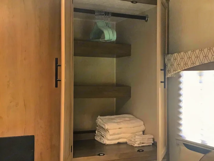 RV rental closet: Organized storage with a hanging rod, shelves, and neatly folded white towels.. Forest River Coachmen Freelander 2019