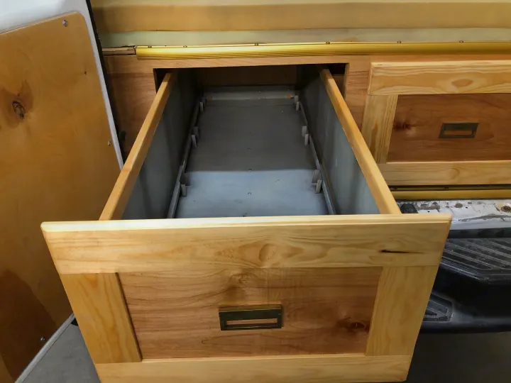 Spacious custom wood drawer system in an RV rental, open for storage. Ideal for organizing your road trip necessities.. Ford E250 Camper Van 2001
