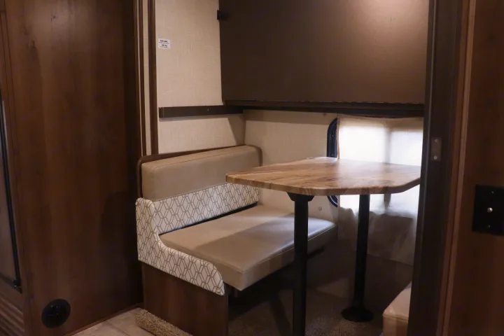 Cozy RV rental dinette with patterned bench seating, a sturdy table, and overhead storage for a comfortable camper experience.. Coachmen Freelander 2020