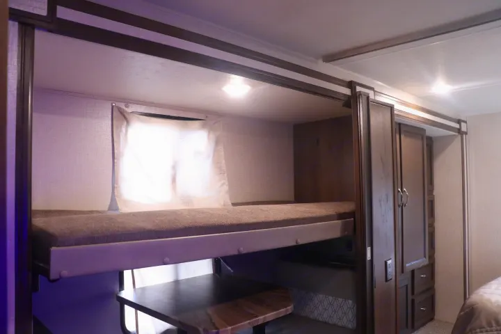 RV rental: Modern interior featuring a lower bunk bed with a table below, next to storage cabinets, perfect for travel.. Coachmen Freelander 2020