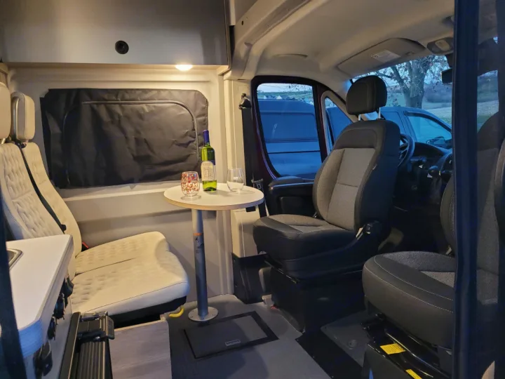 Cozy RV rental interior: A spacious camper van with seating, a table for drinks, and a small kitchenette, perfect for travel.. Winnebago Solis 2022