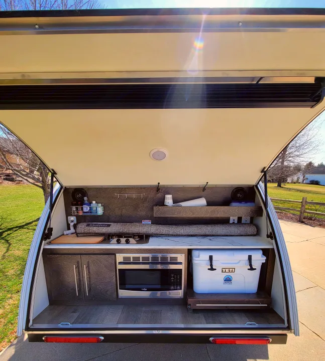 Compact RV rental: Rear galley kitchen with stove, microwave, cooler, and storage in a teardrop camper.. nuCamp T@G 2020