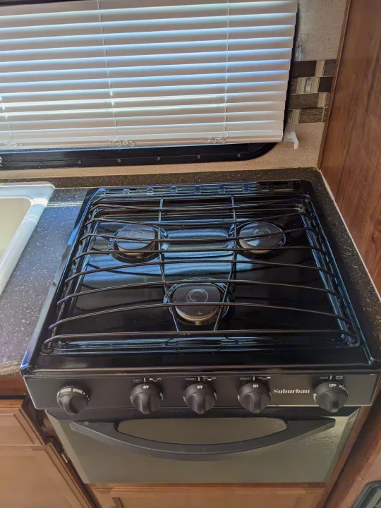 RV rental kitchen featuring a Suburban gas range and oven, perfect for cooking on the road.. Coachmen Freedom Express 2016