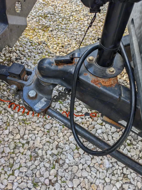 Essential RV rental trailer hitch connection with safety chains and breakaway cable for secure towing over gravel.. Coachmen Freedom Express 2016