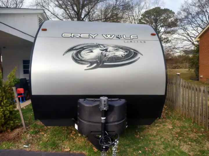 Front of a silver and black Grey Wolf travel trailer for rv rental, parked in a grassy yard.. Forest River Cherokee Grey Wolf Special Edition 2021