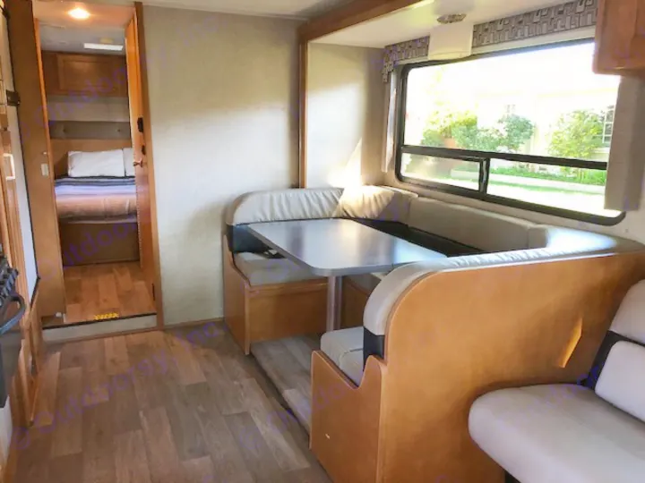 Spacious RV rental interior: well-lit dinette with large window, and a peek into the comfortable bedroom area.. Winnebago Minnie Winnie 2019