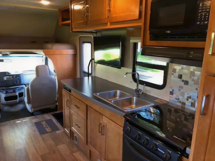 Spacious rv rental interior featuring a full kitchen, overhead bunk, and front cab area. Ready for your next adventure!. Winnebago Minnie Winnie 2019