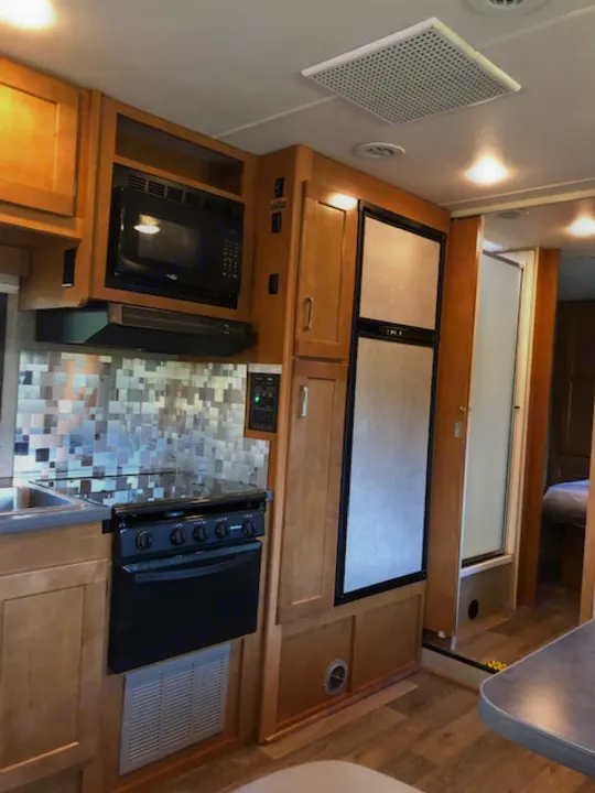 RV rental with a functional full kitchen: microwave, stovetop, covered refrigerator, and light wood cabinetry.. Winnebago Minnie Winnie 2019