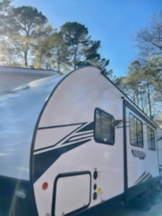 This sleek white travel trailer RV rental, with black graphics, is parked outdoors, ready for your next camping adventure.. Forest River Tracer 2022