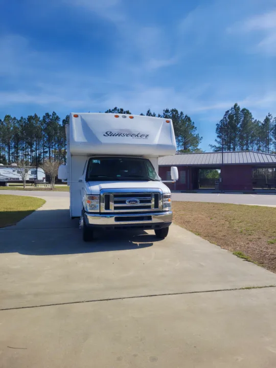 White Sunseeker Class C RV rental parked at a sunny campground. Blue sky and trees in background.. Forest River Sunseeker 2013