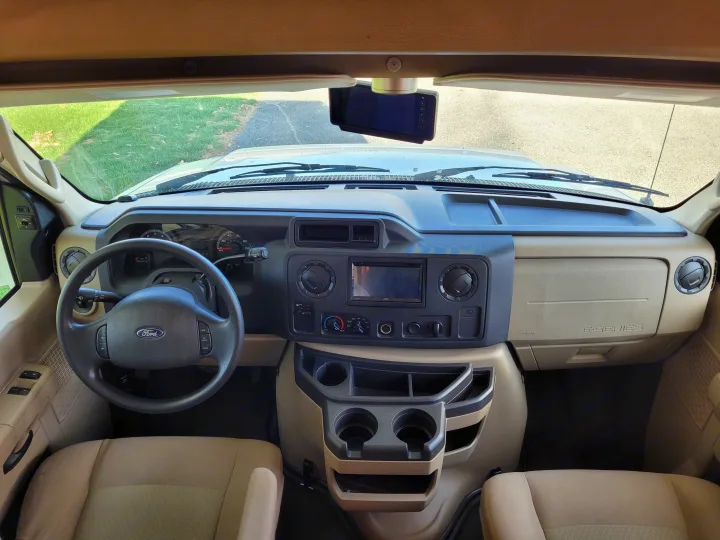 Inside an RV rental: View of the Ford E-Series cockpit, dashboard, steering wheel, and infotainment system.. Forest River Sunseeker 2013
