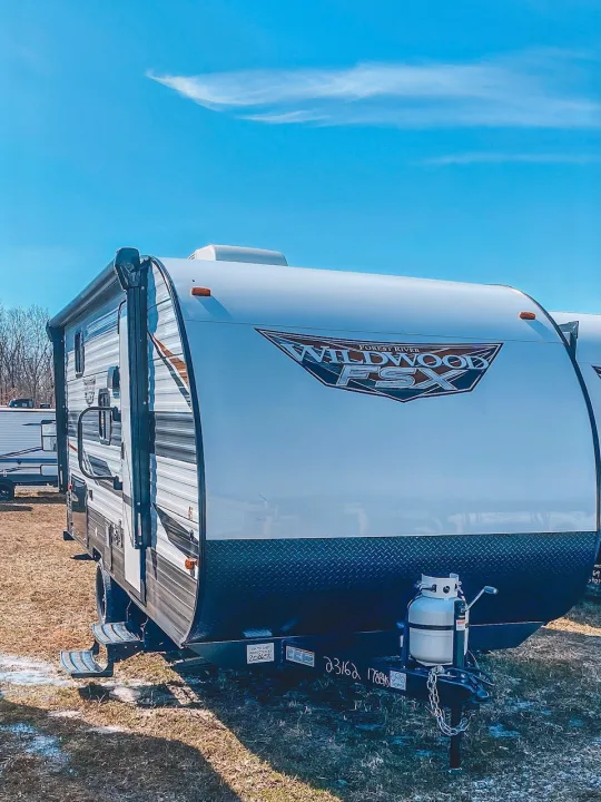 Explore with this white & black Wildwood travel trailer, ideal for your next RV rental adventure! Parked under a clear blue sky.. Forest River Other 2022