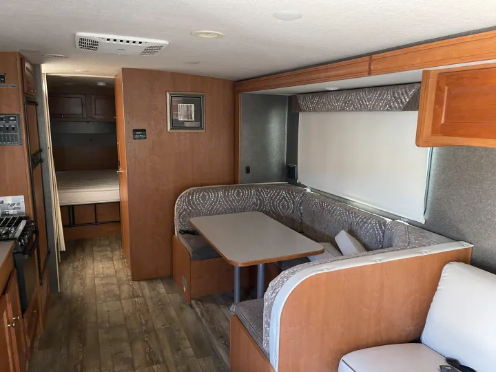Inside this **rv rental**, a bright and clean living space with a dinette, kitchen on left, and bedroom access visible.. Winnebago Vista 2016
