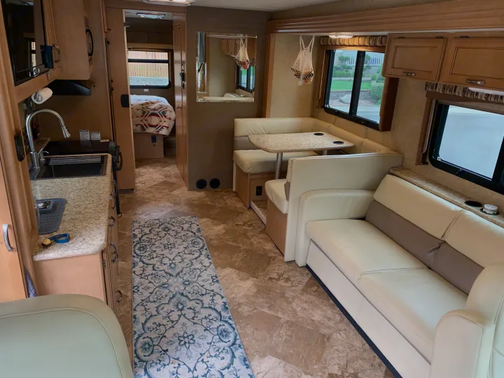 This RV rental's spacious interior highlights a full kitchen, comfortable dining booth, living area sofa, and peek into the bedroom.. Other A.C.E 2016