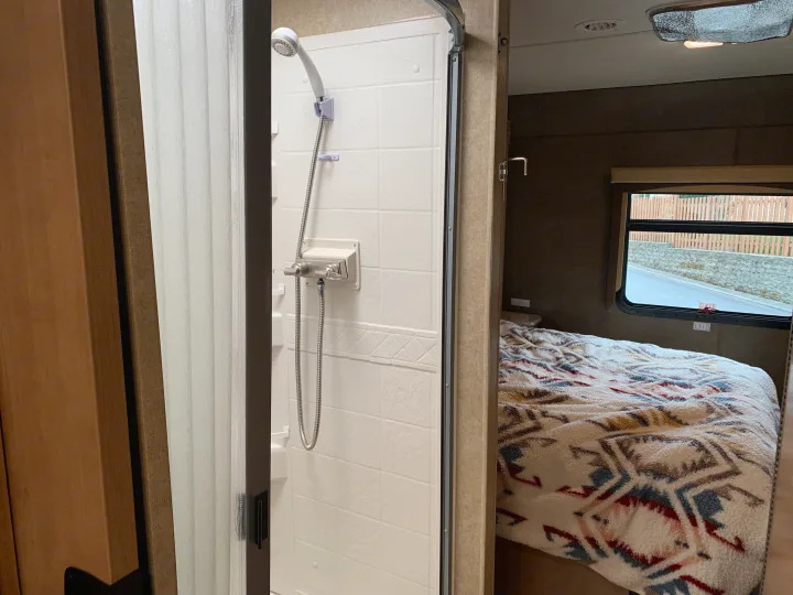 Experience comfort in your RV rental with this compact shower and cozy bedroom featuring a patterned blanket.. Other A.C.E 2016