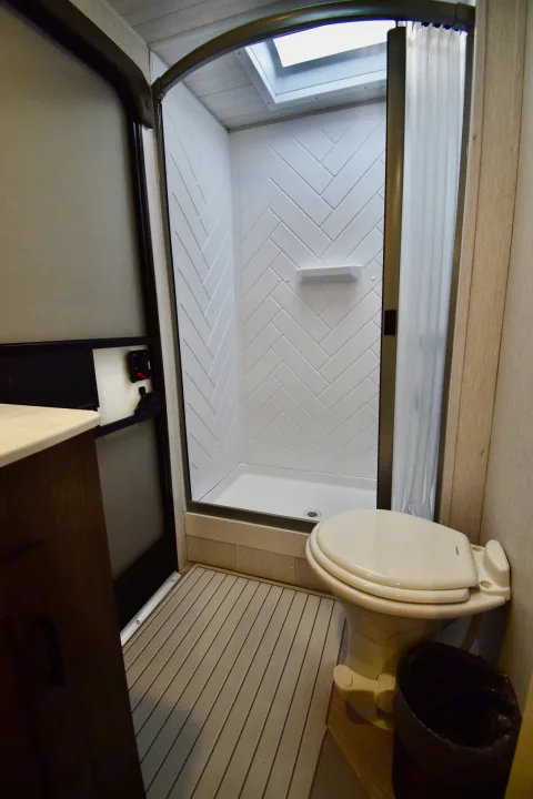 This RV rental features a compact bathroom with a bright shower, herringbone walls, skylight, and toilet.. Forest River Other 2022