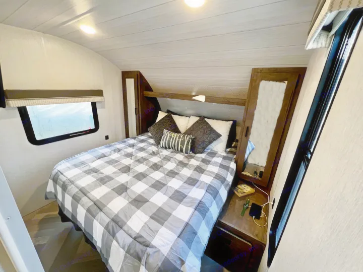 Cozy RV rental bedroom with a grey and white checkered bed, side cabinets, and a window for a comfortable stay.. Forest River Other 2022