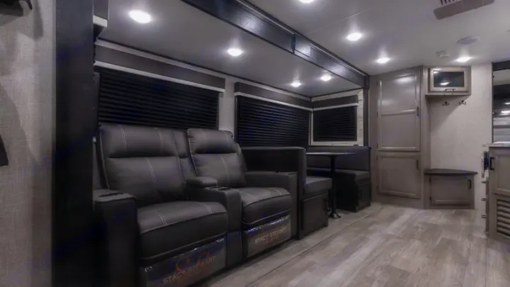 Modern RV rental interior: cozy living space with plush recliners, a dinette, and gray wood-look flooring. Ready for your adventure!. Jayco Jay Feather 2022