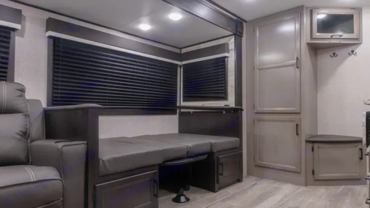 An RV rental interior showing a convertible dinette, leather sofa, ample storage, and entertainment unit. Compact travel comfort.. Jayco Jay Feather 2022
