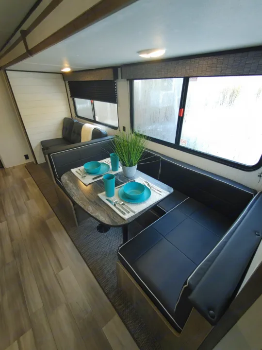 Modern rv rental interior showing a comfortable dining booth, set table, and large window for scenic views.. Heartland Pioneer 2022