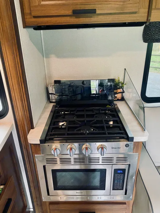 RV rental kitchen showing a Magic Chef gas stove, built-in microwave, and counter. Compact and functional.. Forest River Sunseeker 3250DSLE 2022