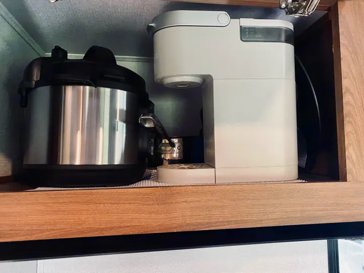 RV rental: A compact cabinet in an RV kitchen holds a stainless steel pressure cooker and a white coffee maker.. Forest River Sunseeker 3250DSLE 2022