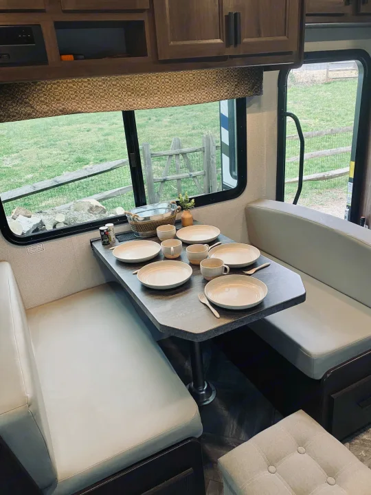 Cozy RV rental dinette featuring a set table, comfortable bench seating, and a scenic outdoor view through the window.. Forest River Sunseeker 3250DSLE 2022