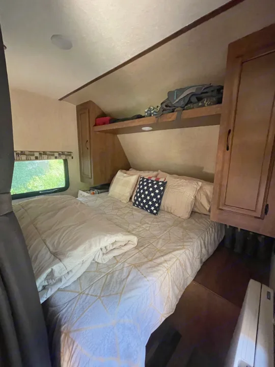 Comfortable bedroom in an RV rental, showing a bed, window, and built-in storage. Ideal for travel.. Starcraft Autumn Ridge 2018