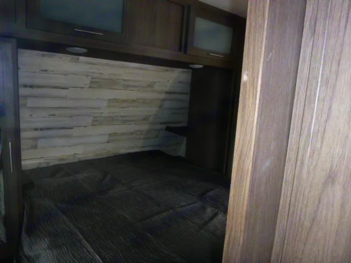 Inside an RV rental: a modern bedroom with a comfortable bed, wood-paneled headboard, and convenient storage cabinets.. Dutchmen Kodiak Ultra Lite 2021