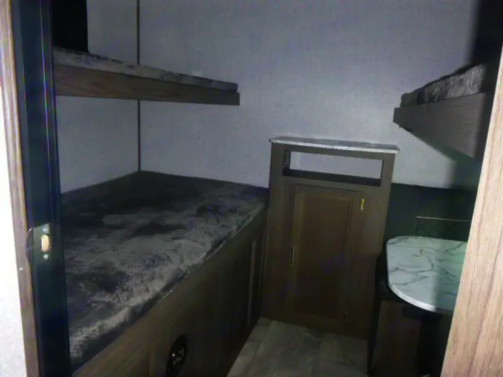 RV rental interior featuring bunk beds, a small cabinet, and a dining table with seating.. Dutchmen Kodiak Ultra Lite 2021
