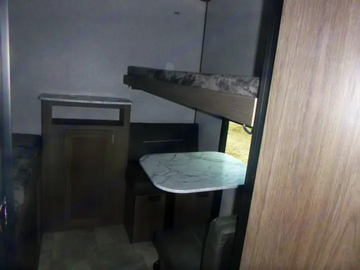 RV rental interior view: Bunk beds above a dinette and storage cabinet, showcasing compact and functional living.. Dutchmen Kodiak Ultra Lite 2021