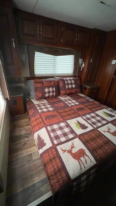 RV rental bedroom: Features a full bed with a rustic quilt, overhead storage, and wood-look flooring for a cozy stay.. Forest Rivers Georgetown 2013