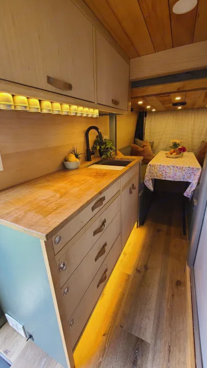 Stylish RV rental interior: featuring a custom wood kitchen, integrated lighting, and cozy dining space.. Mercedes-Benz Sprinter 2019